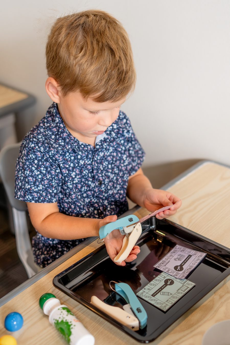 A preschooler building fine motor strength with a handheld paper puncher at Hope Kids Preschool