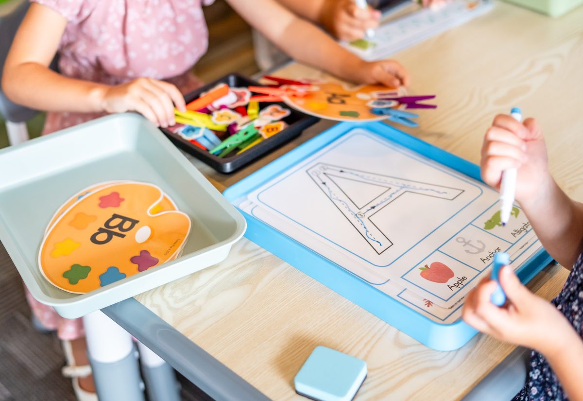 Preschoolers tracing the letter A and sorting letter tiles during a literacy lesson at Hope Kids Preschool